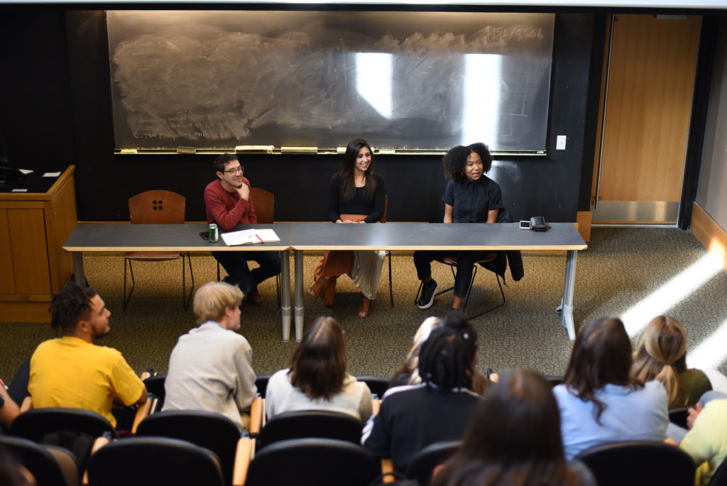Prof Rattner and two alumni guest speakers sit and talk to a crowd in a lecture hall