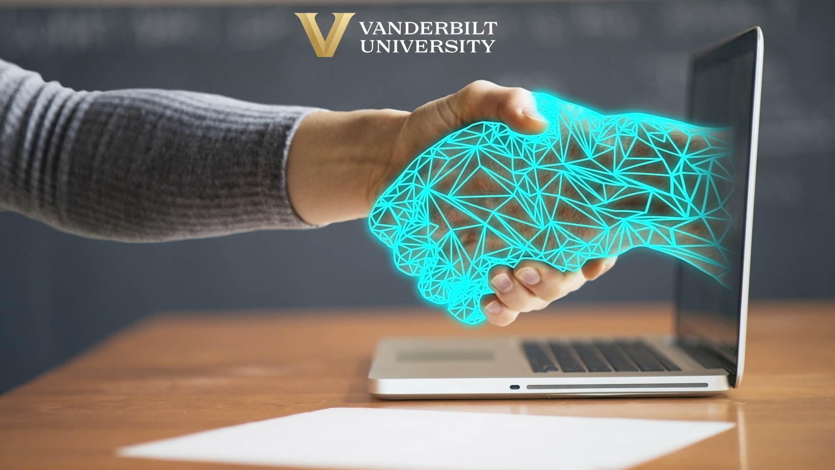 A human hand shakes a virtual hand coming out of a computer 